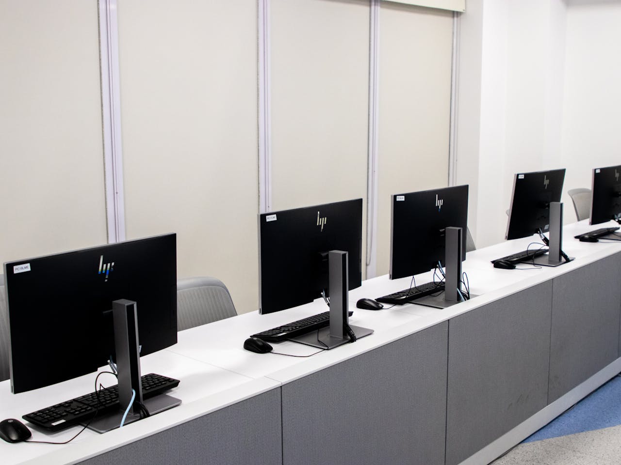 Minimalist open office space featuring empty computer desks with monitors.