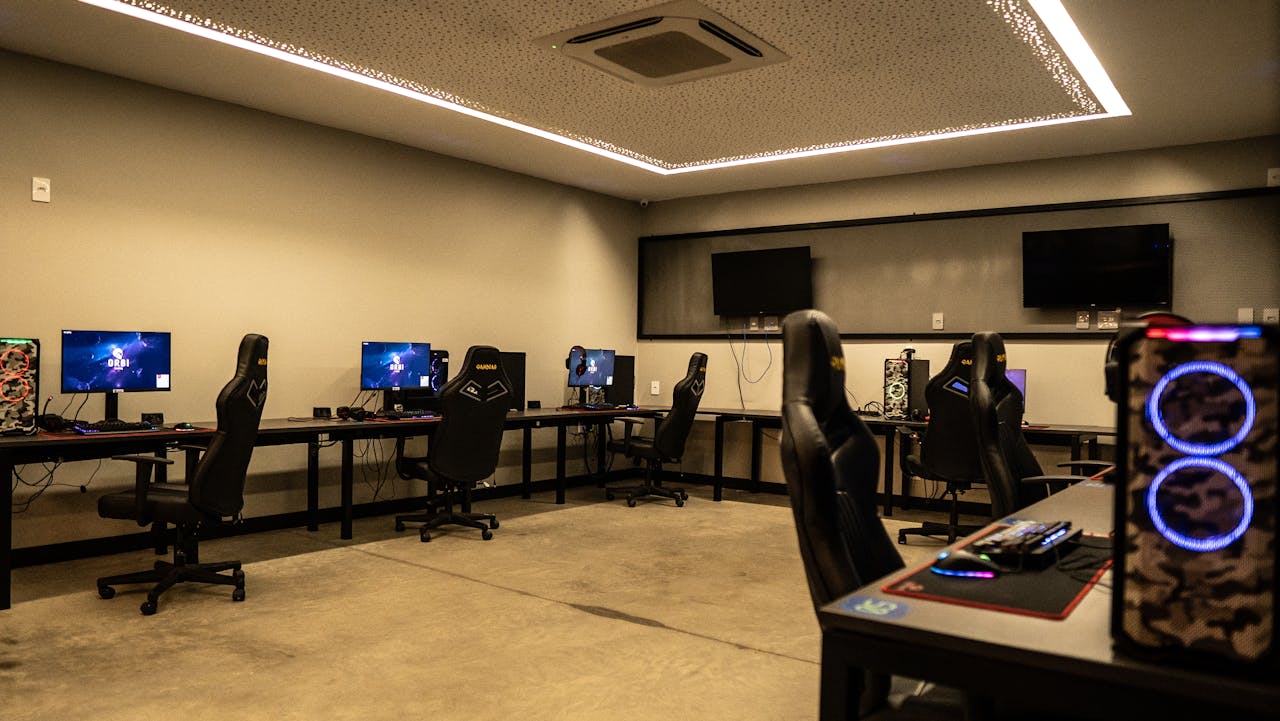 A modern gaming room featuring high-performance PCs, gaming chairs, and sleek design.